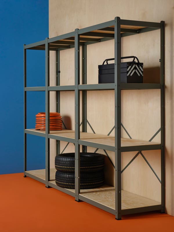 BROR shelving units holding tyres, a hose and a toolbox, placed by a wall in a room with a blue wall and orange floors.