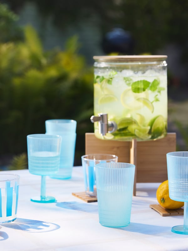 أكواب KALLSINNIG وPILLERSTARR زرقاء على طاولة خارجية بجانب برطمان IKEA 365+ به عصير ليمون.