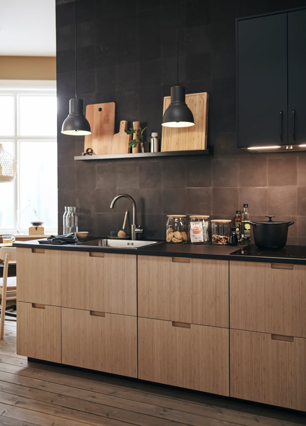 In this modern kitchen, FRÖJERED kitchen fronts in bamboo are paired with black tiled walls and accessories.
