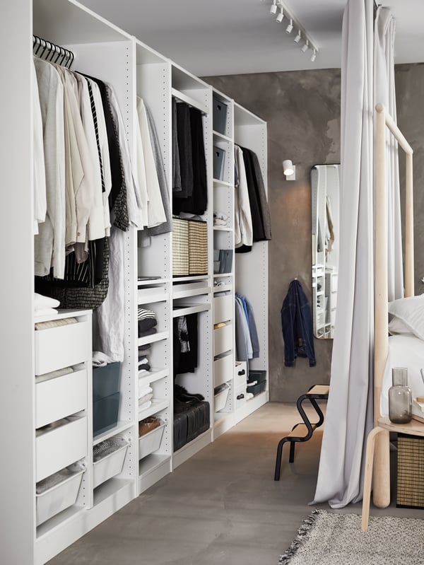 Living-room where one wall is fitted with open, floor-length curtains, revealing a wall-wide wardrobe arrangement.