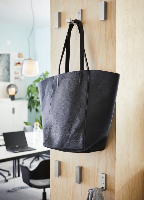 BJÄRNUM aluminium folding hooks mounted to a partition wall, with a black tote hanging on one hook.