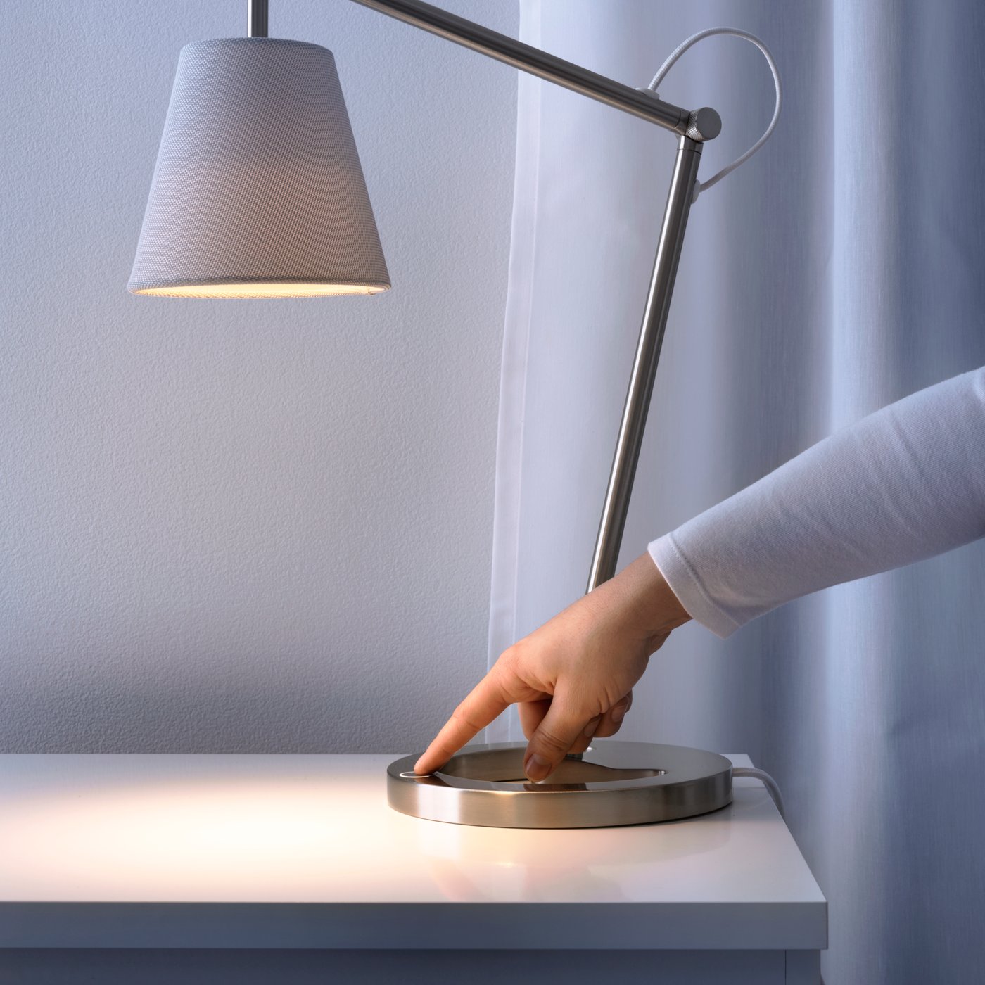 A person powering on a table lamp.