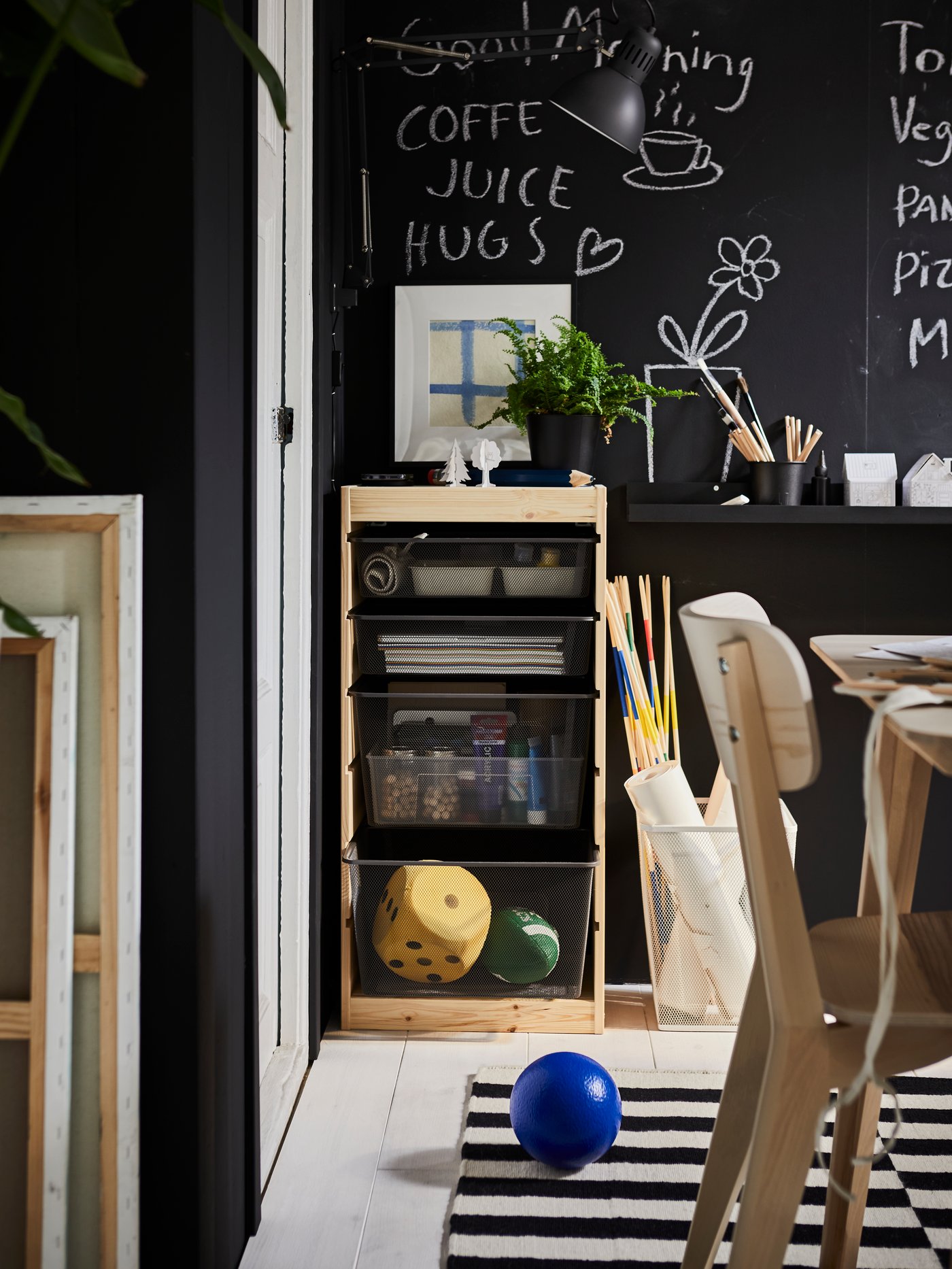 Un comedor con una pizarra en una pared y bajo la pizarra un mueble organizador TROFAST con cajas metálicas.