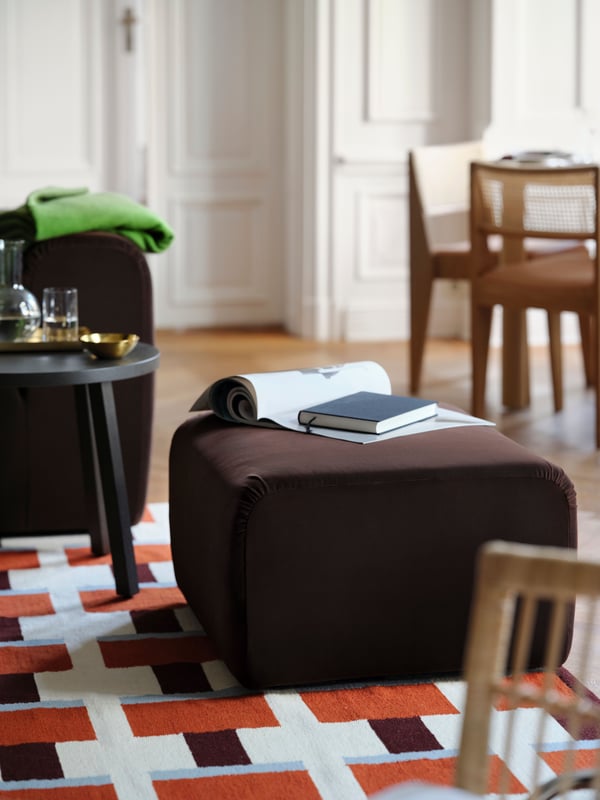 Dnevna soba sa STOCKHOLM 2025 ravno tkanim tepihom na parketu. Sofa dvosed, tabure i pomoćni stočić na tepihu.