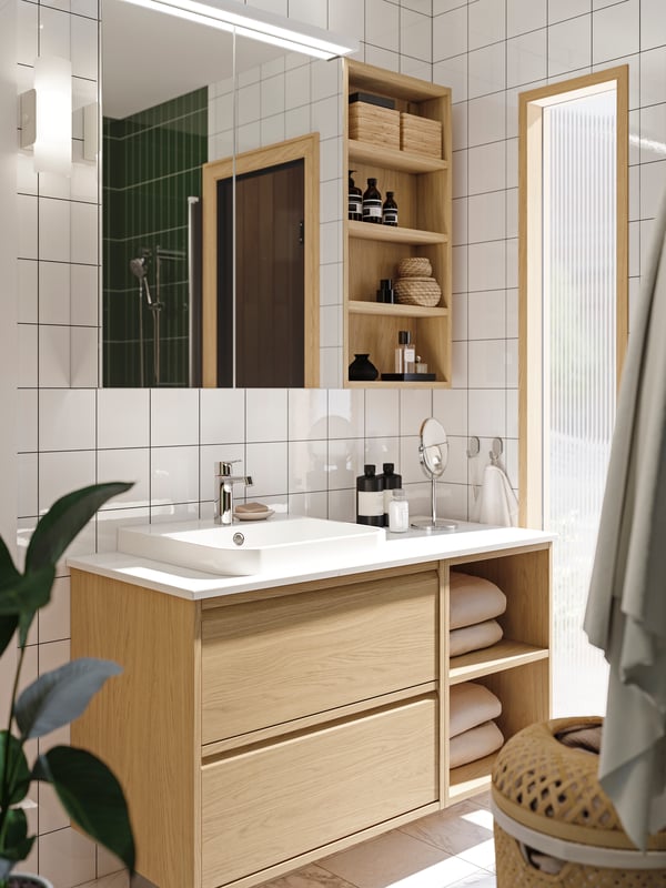 A bathroom has open and closed storage and an ÄNGSJÖN vanity in oak effect with a white BACKSJÖN semi-recessed sink.