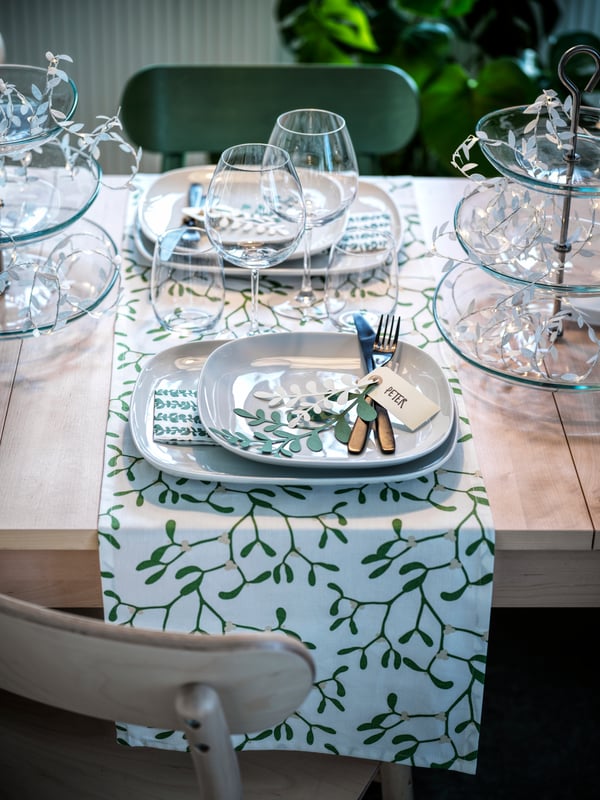 Table décorée pour Noël avec des tapis blancs et des détails verts.