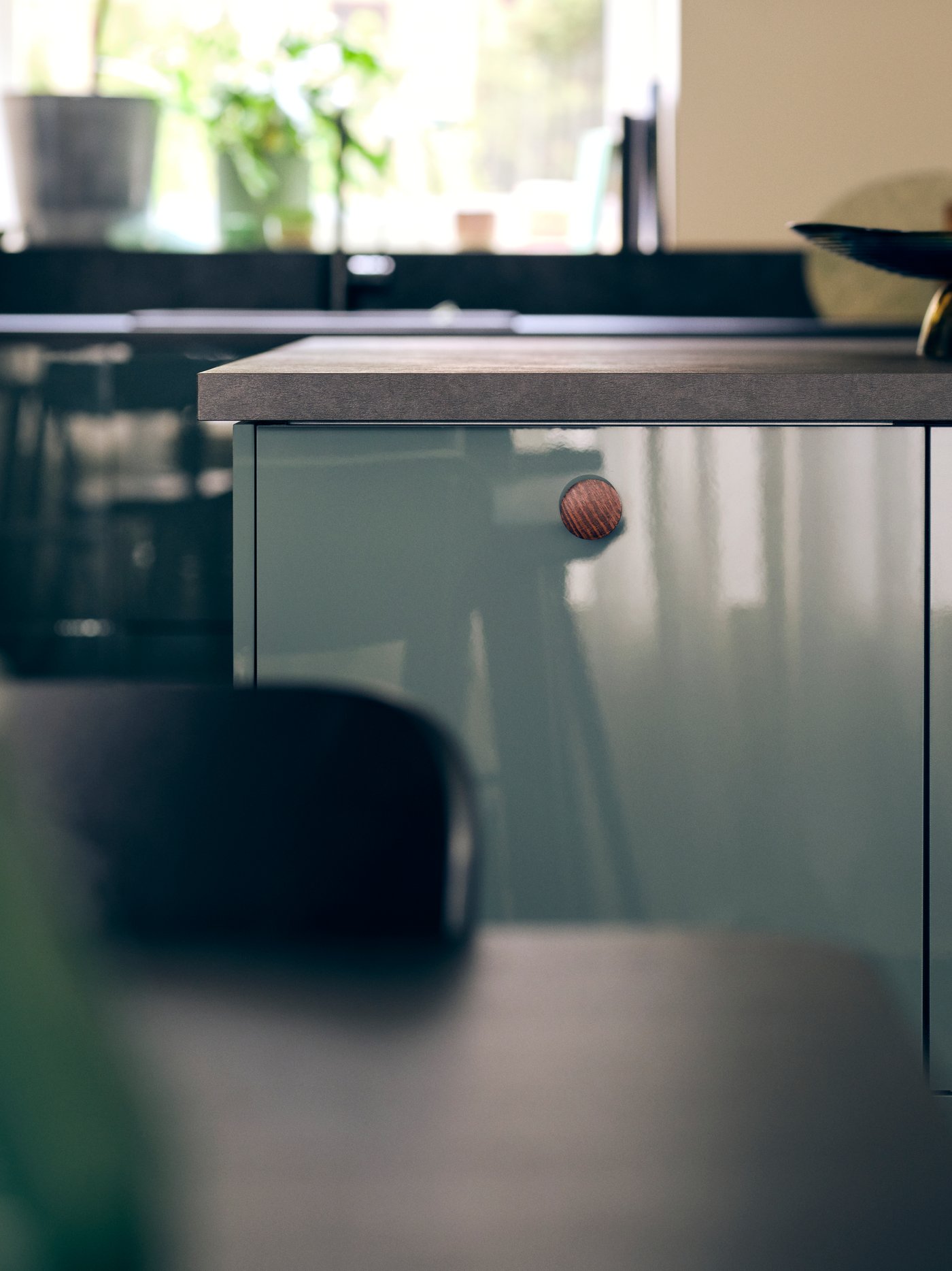 A kitchen with KALLARP high-gloss dark grey green kitchen fronts and an EKBACKEN worktop in black laminate with a bowl.