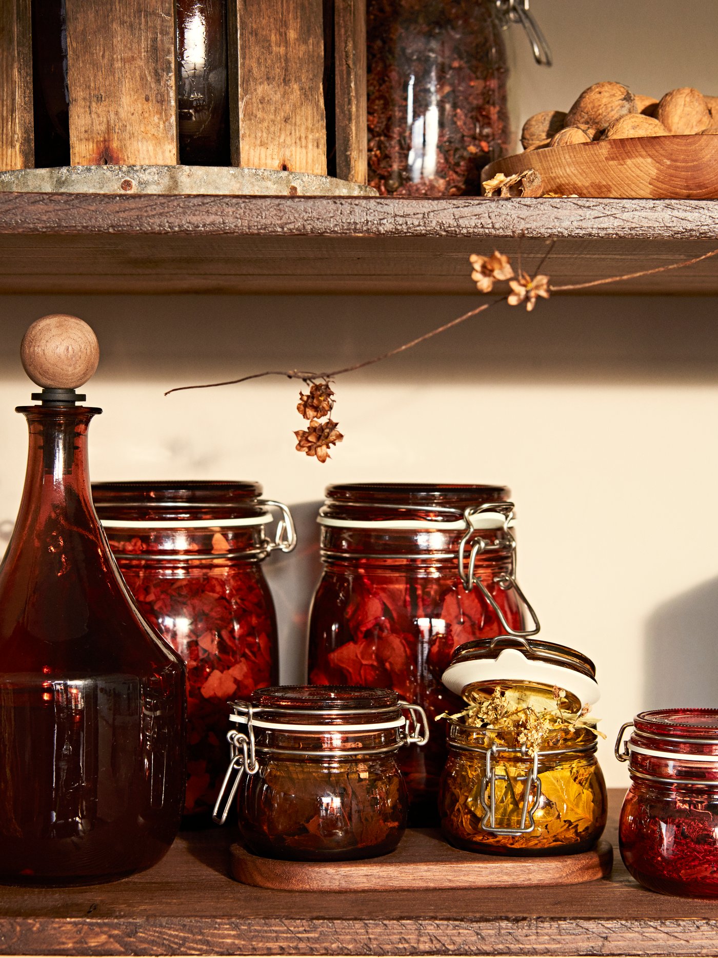 A range of KRÖSAMOS glass jars with lids of varying sizes on a kitchen countertop. They are storing herbs and tea blends.
