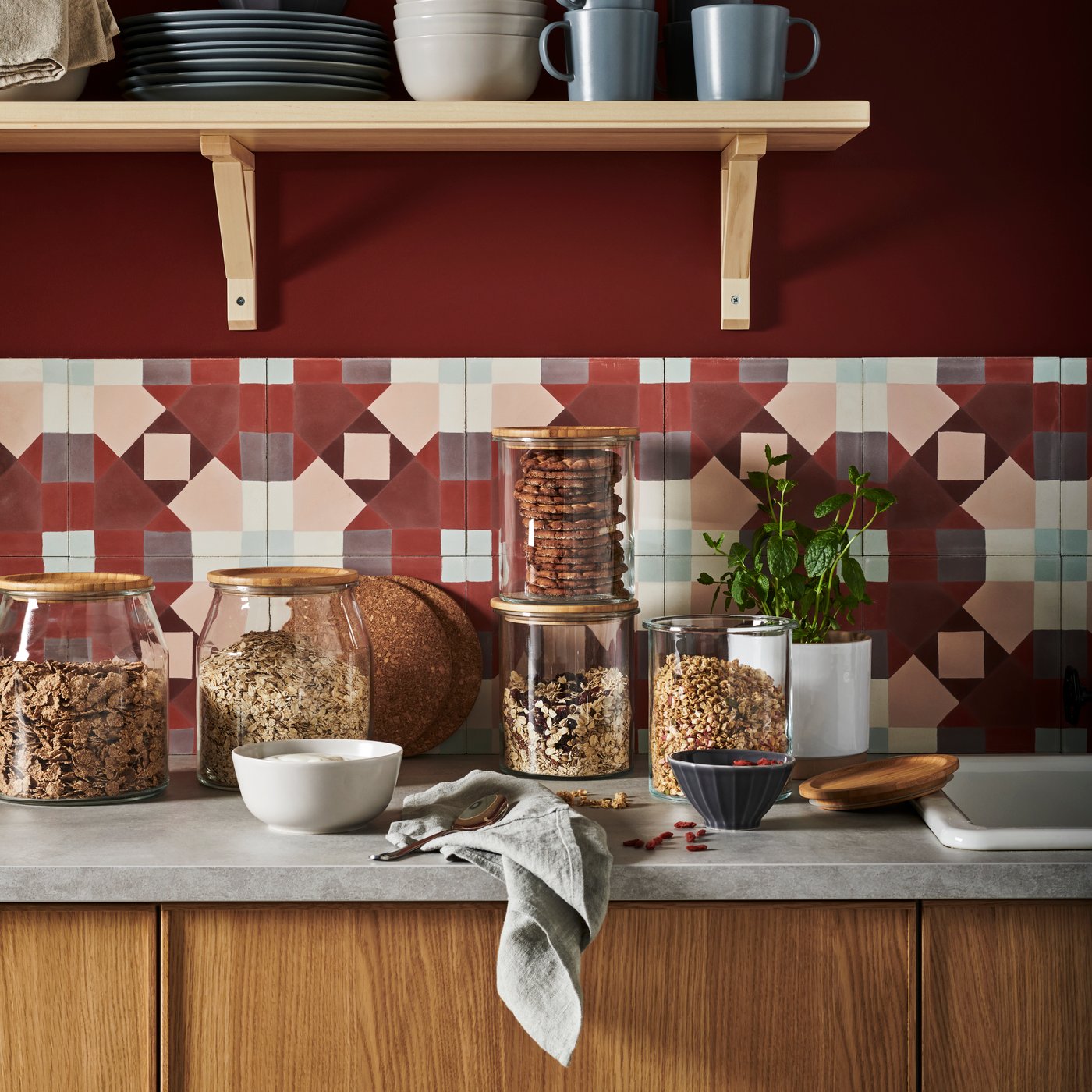 A kitchen with oak fronts with a grey worktop and IKEA 365+ food containers in glass with bamboo lids on top holding various pasta and grains.