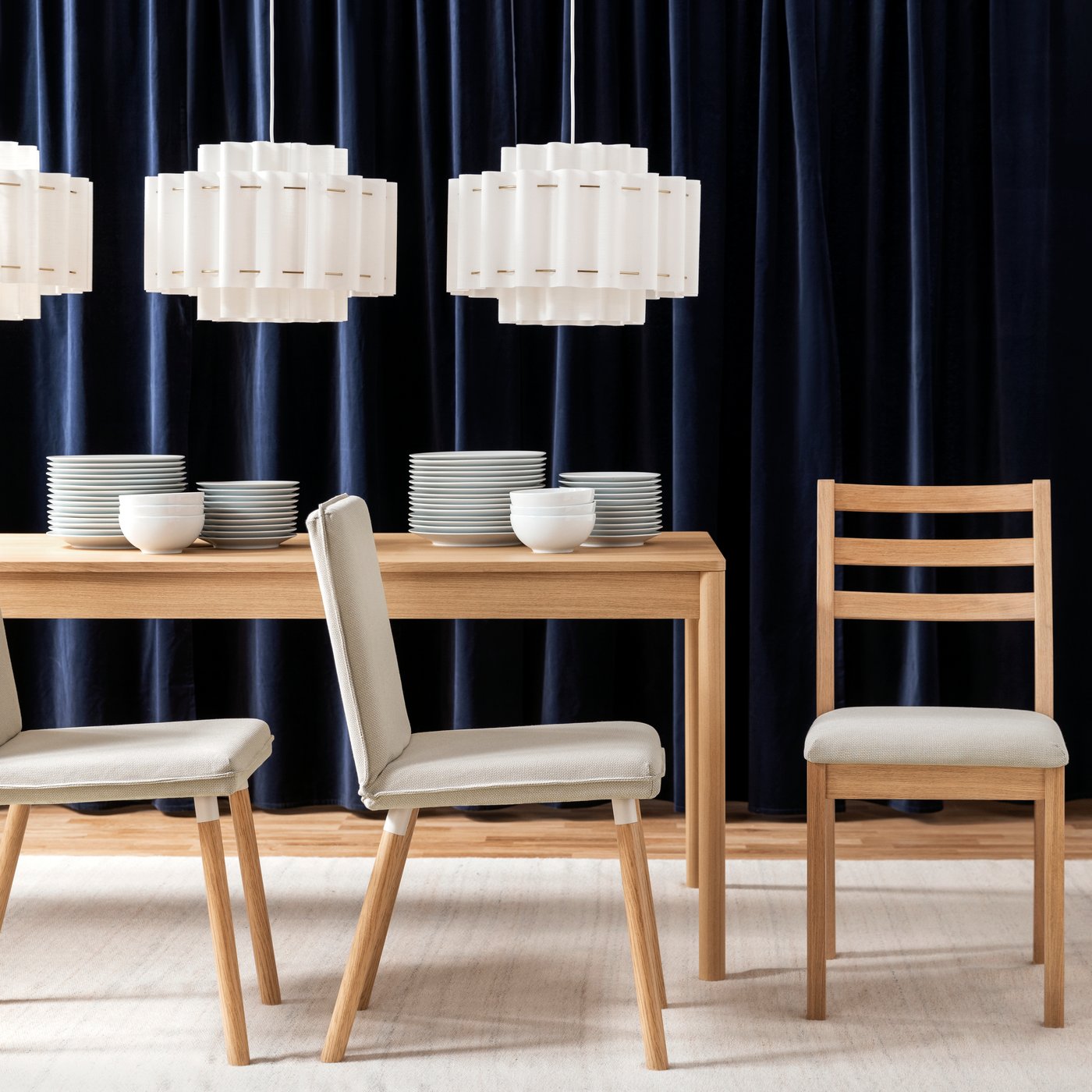 A bright dining space with a light wood TONSTAD chair beside a table set with plates and vases under stylish lamps.