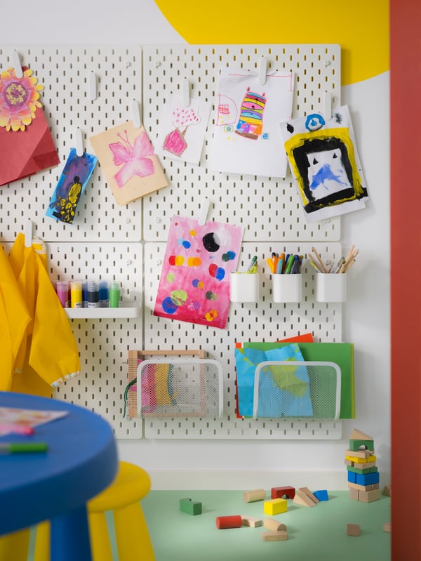Un tablero SKÅDIS  en la pared de un dormitorio infantil organizando útiles de colegio.