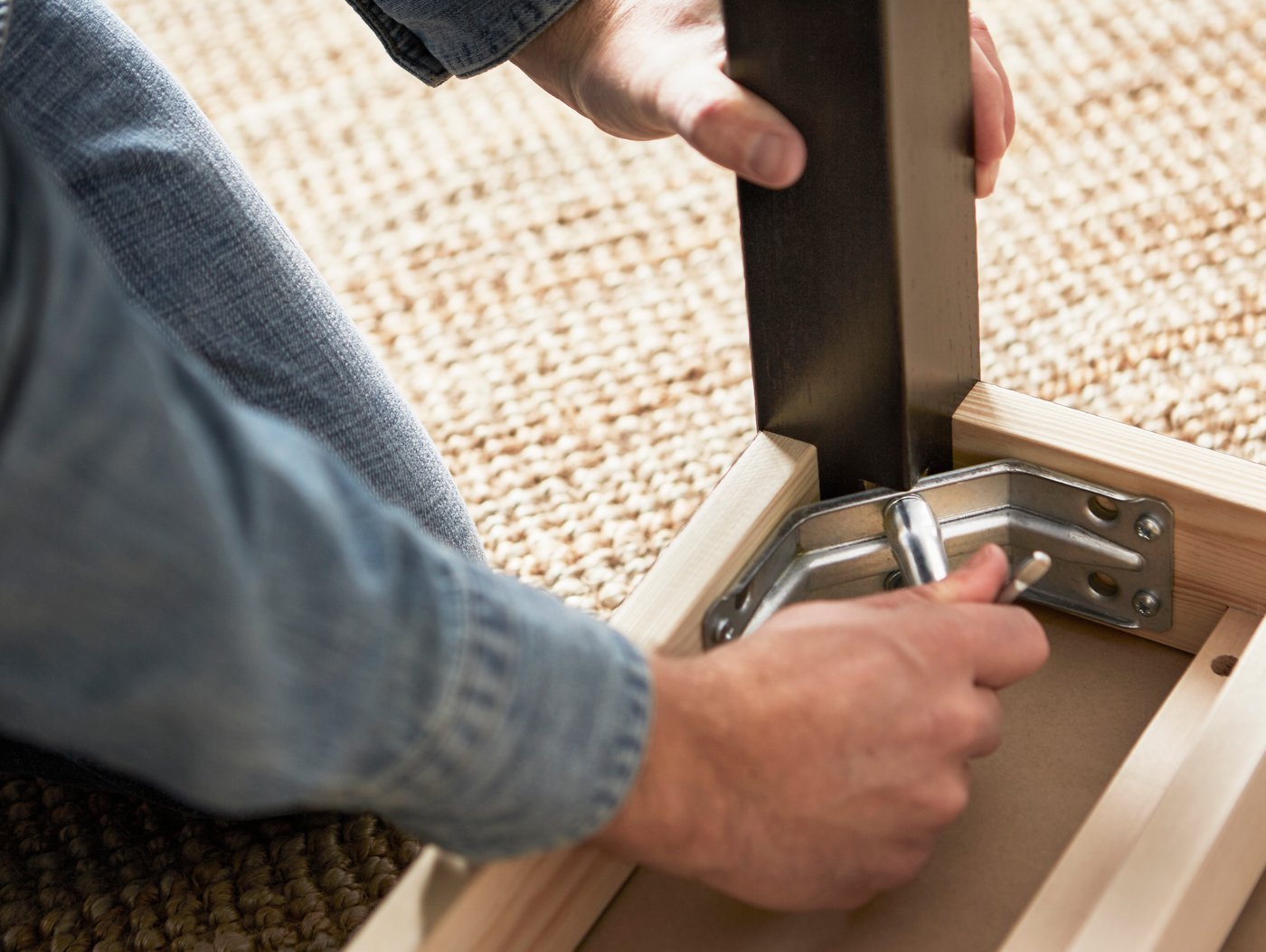 A man screws in a bolt into the leg of a chair 