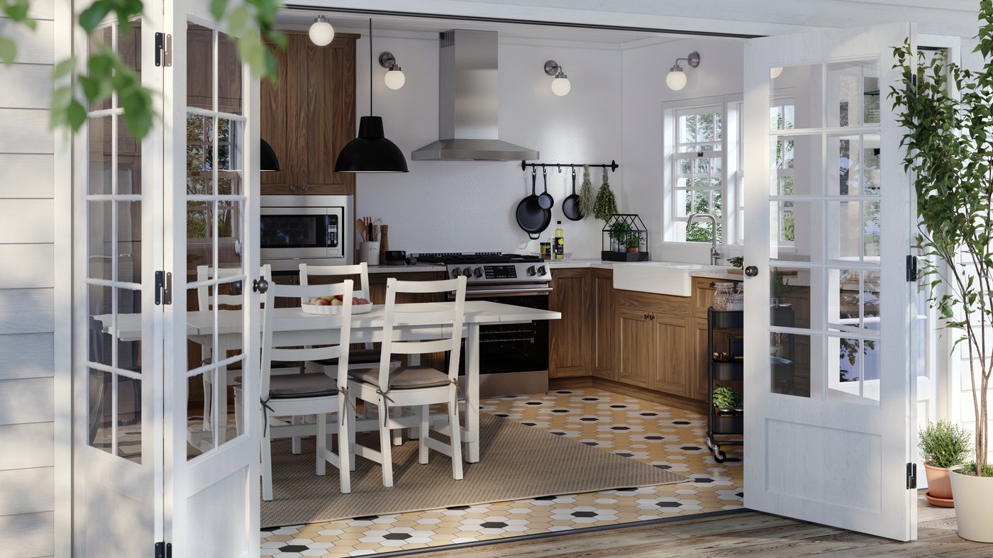 A sunny kitchen with walnut-effect ENKÖPING doors on the cabinets and a white table with four chairs around it.