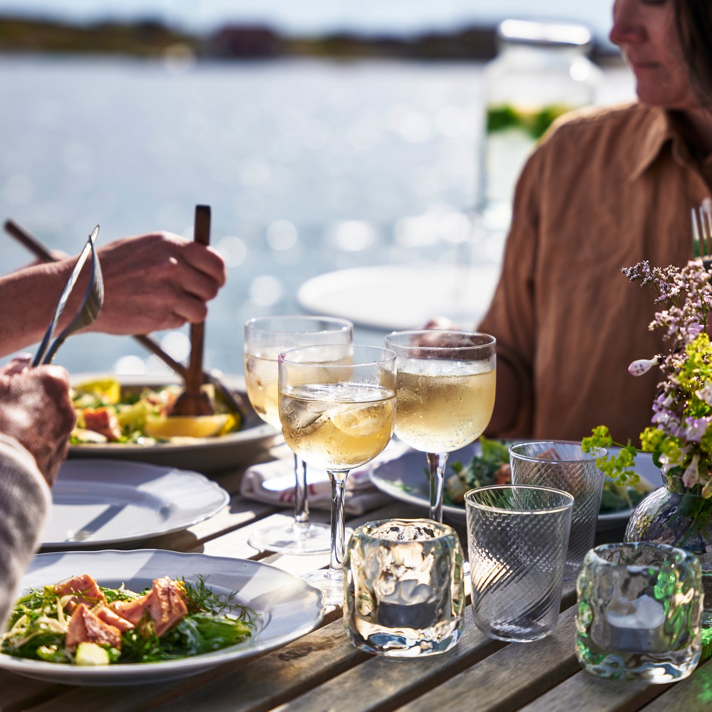 Une famille assise au bord de l’eau partageant un repas