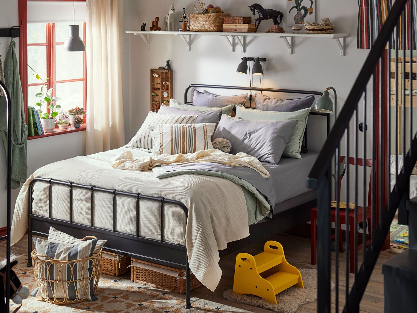 Family bedroom with STJÄRNÖ bed frame in anthracite with bedding in pastel colours, bright yellow step stool by bed.