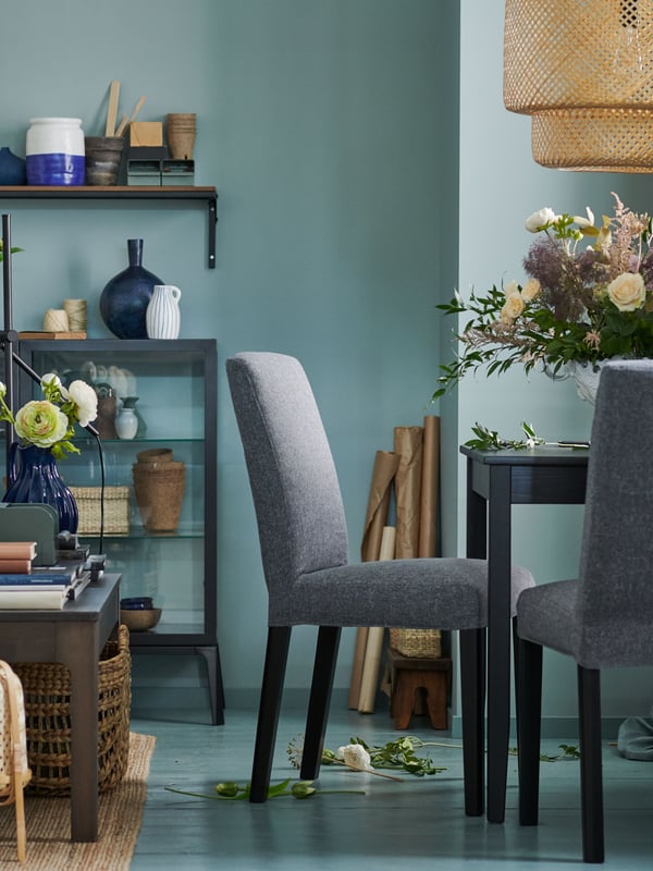 Silla BERGMUND con forro gris y patas negras junto a mesa de comedor negra.