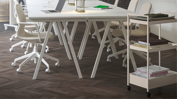 Un espace de bureau réaménagé, avec quatre bureaux TROTTEN blancs regroupés, associés à des fauteuils de réunion LÅNGFJÄLL beiges et blancs.