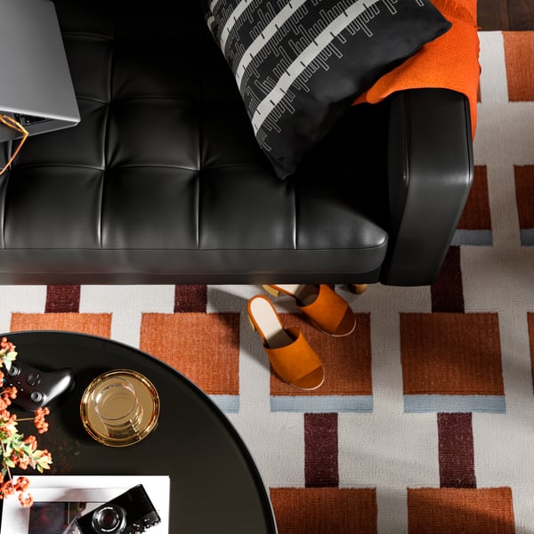 A leather and coated fabric 3-seat sofa stands on a STOCKHOLM 2025 rug opposite a FRÖTORP coffee table. 