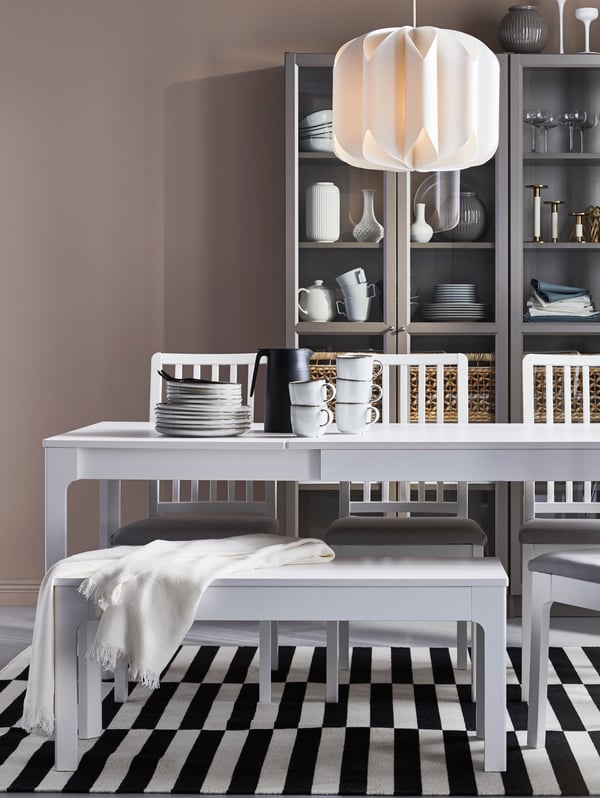 A dining area in white tones with a white EKEDALEN table, MOJNA lamp and STOCKHOLM rug.
