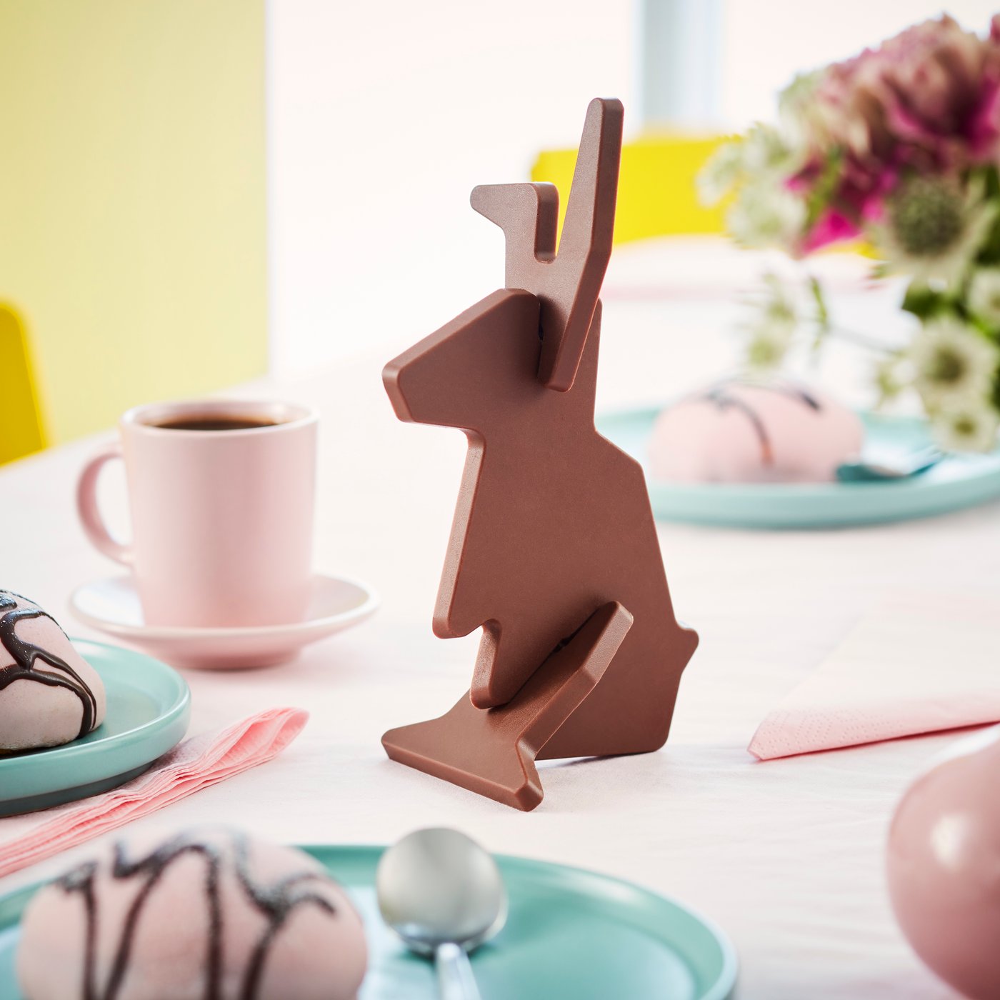 A VÅRKÄNSLA milk chocolate bunny placed on a set up table with some coloured eggs.