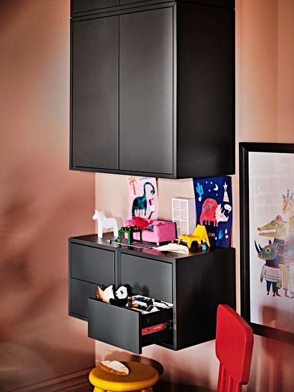 Two dark grey EKET cabinets with 2 drawers with small toys on top, below an EKET cabinet with 2 doors and 1 shelf.