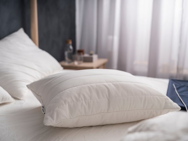 A man, laying on his back, is sleeping deeply on IKEA RUMSMALVA ergonomic pillow.