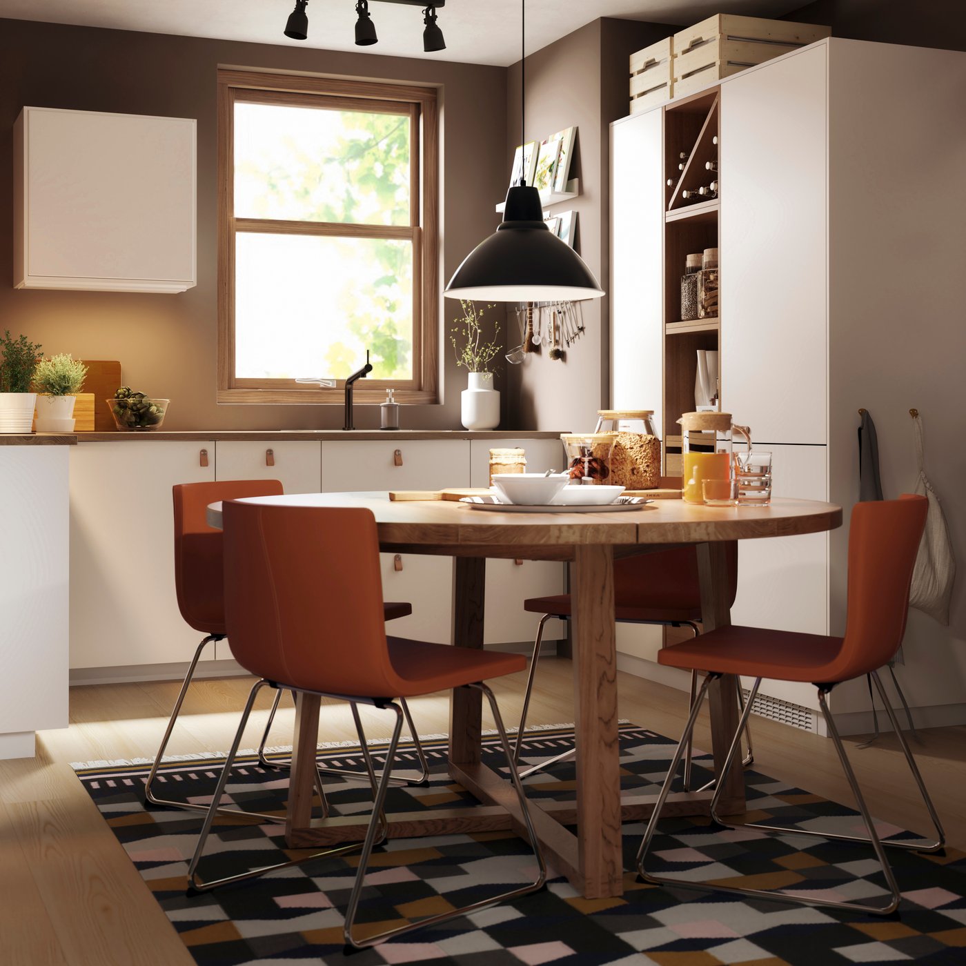MORBYLANGA round dining table in brown-stained oak veneer in a dining room with four BERNHARD chairs around it. A SKURUP pendant lamp hangs above the dining table and a STOCKHOLM rug sits below it.