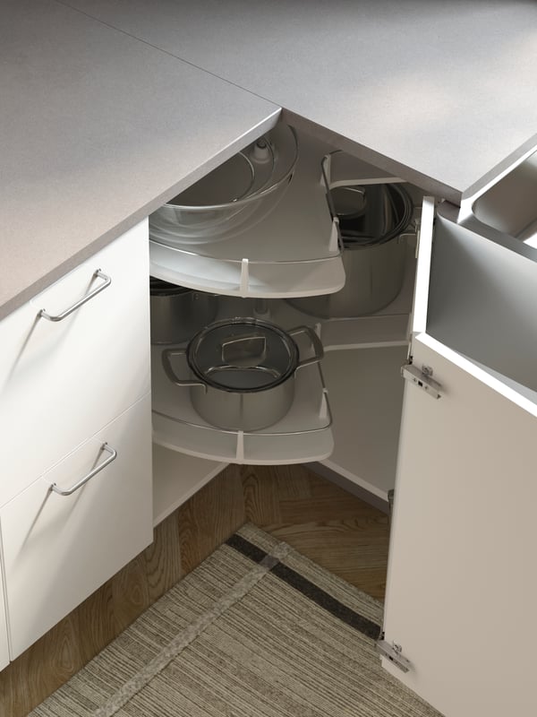 A kitchen with grey worktops and an open corner cabinet in white where an UTRUSTA carousel stores pots, pans and dishes.