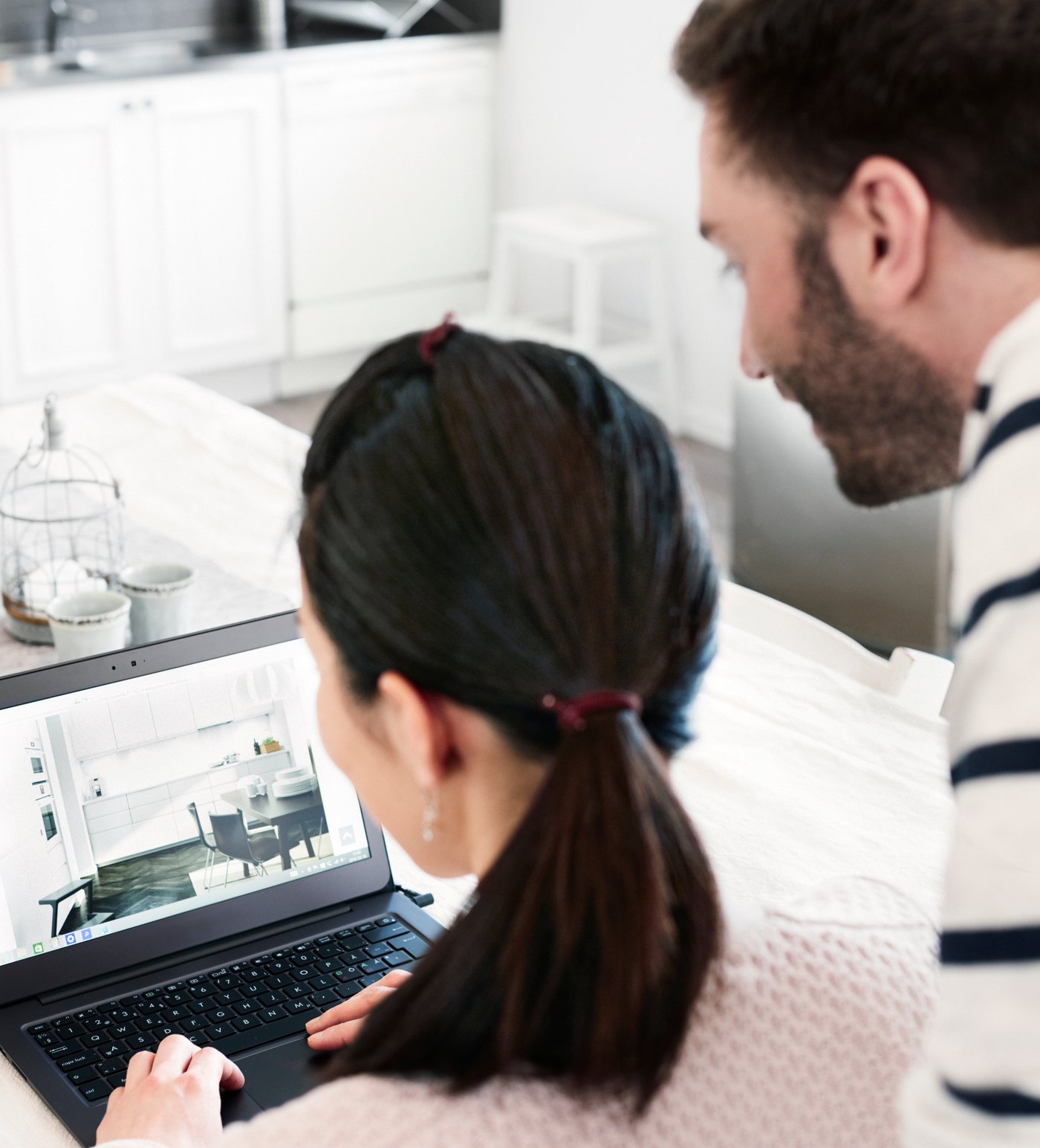 Woman using laptop with man standing beside in bright room