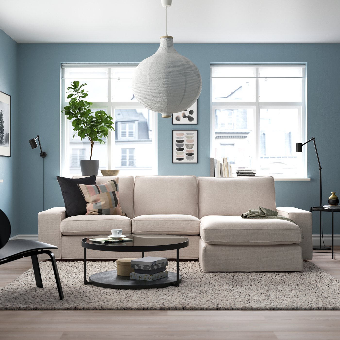 Ein hellbeiges KIVIK-3-Sitzer-Sofa mit Chaiselongue von Tresund im Wohnzimmer.