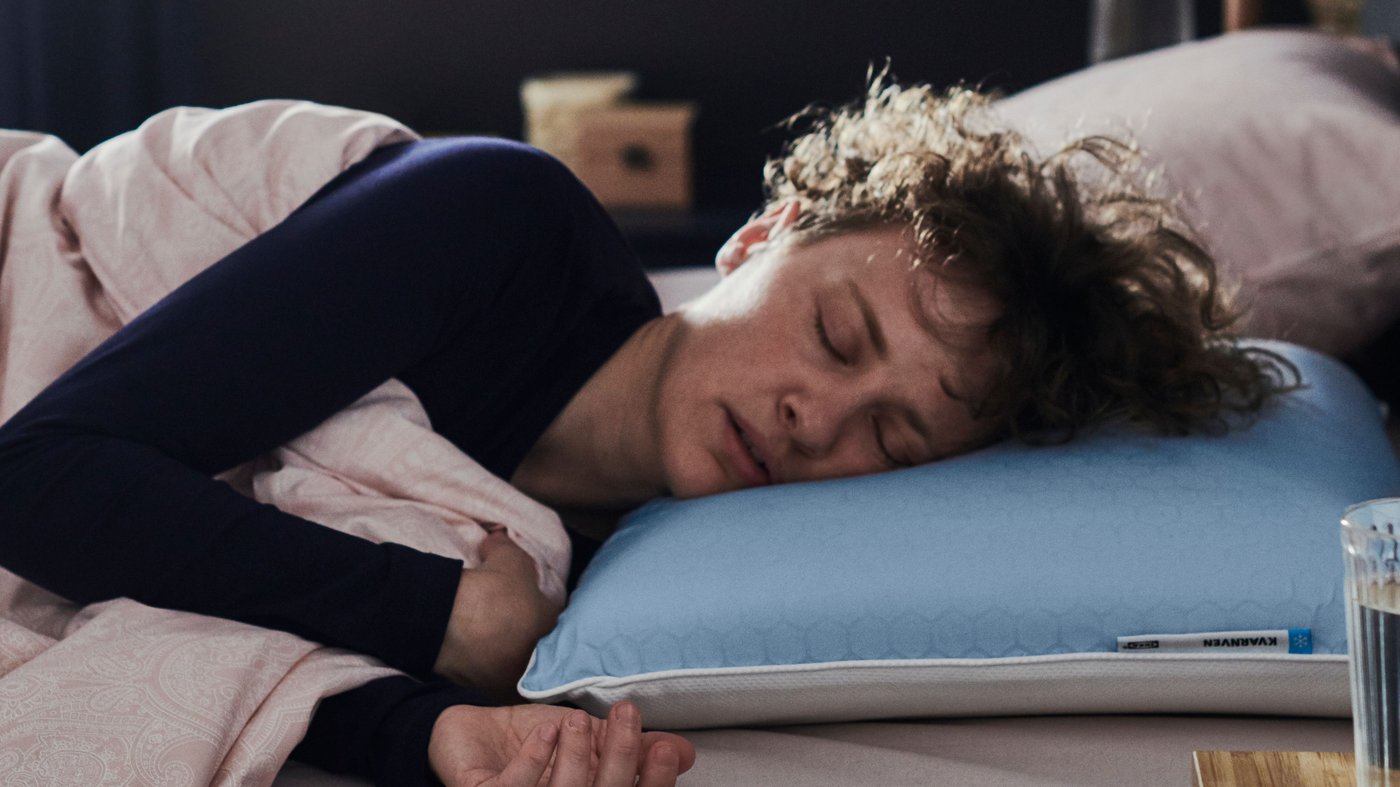Una mujer durmiendo sobre una almohada IKEA con un pijama azul.