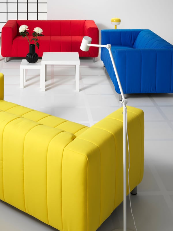 A white living room with a red, blue, and yellow KLIPPAN 2-seater sofa.