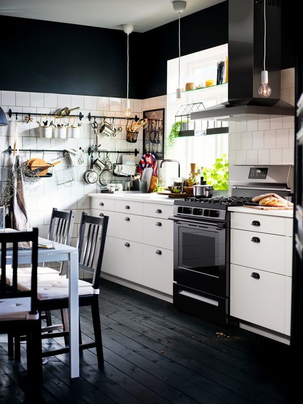 Une cuisine avec des armoires inférieures blanches SEKTION, un comptoir EKBACKEN, une cuisinière MOTSVARIG avec table de cuisson à gaz, et un plancher en bois foncé.