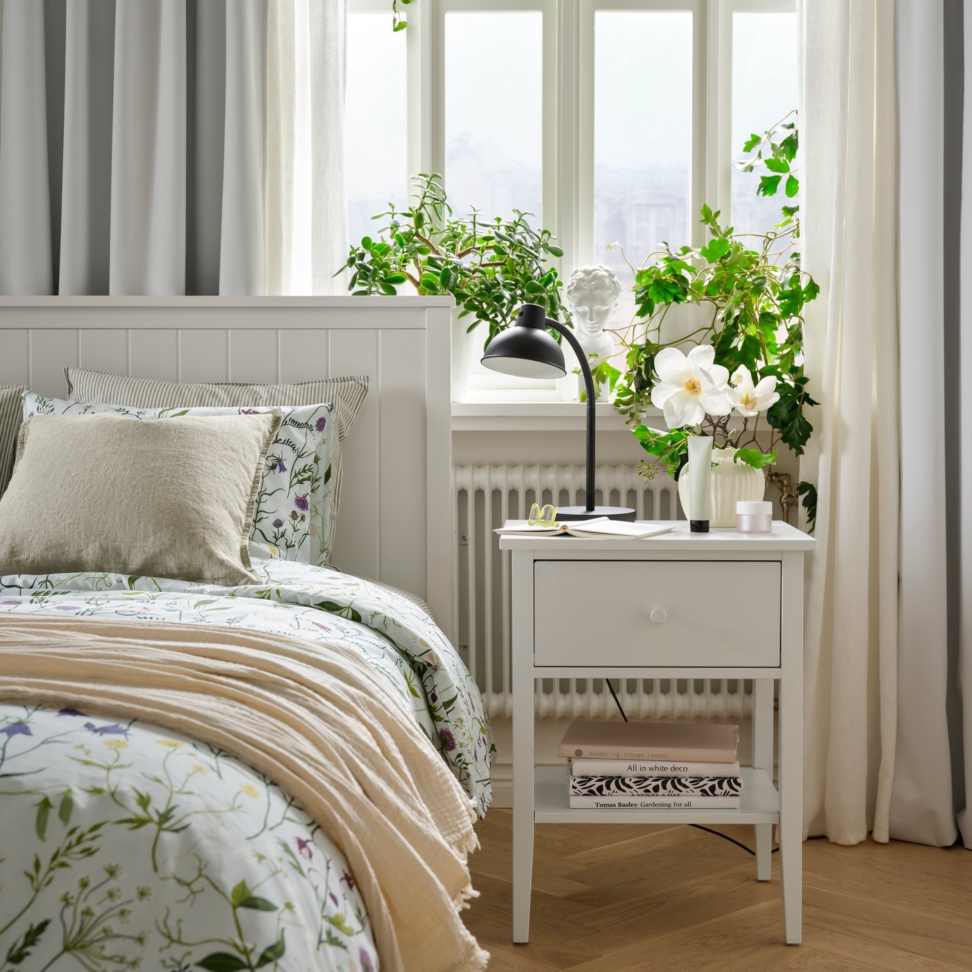 Buró GULLABERG blanco con cajón y repisa junto a una cama GULLABERG con ropa de cama floral, en un dormitorio.