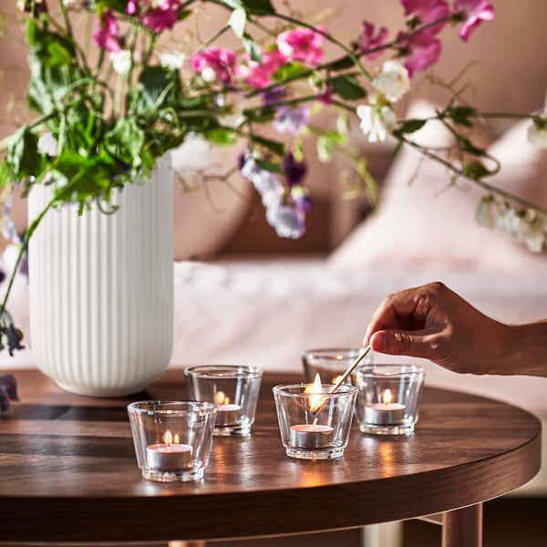 STILREN plant pot and GALIJ tealight holders with a tealight being lit on a coffee table.