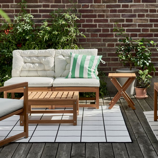 A NAMMARO patio set sits on a deck with white cushions and a white and green striped pillow.
