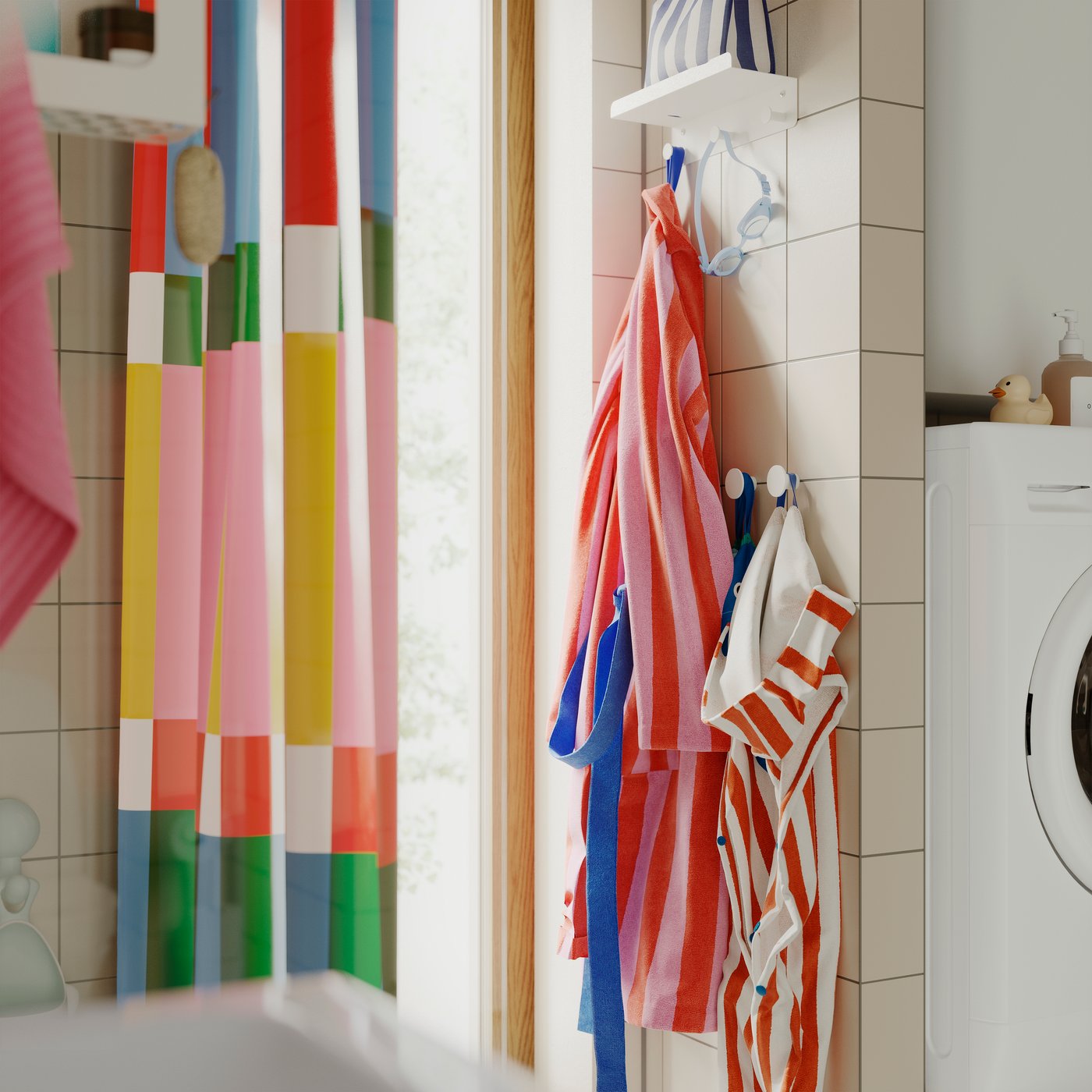 Un baño con una estantería ENUDDEN con 3 ganchos, sosteniendo toallas a rayas y batas coloridas sobre una pared de azulejos.
