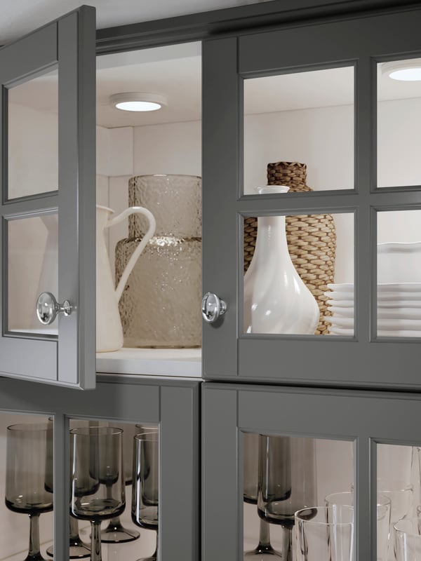 MITTLED integrated lighting inside a METOD kitchen cabinet with other kitchenwares stored inside.