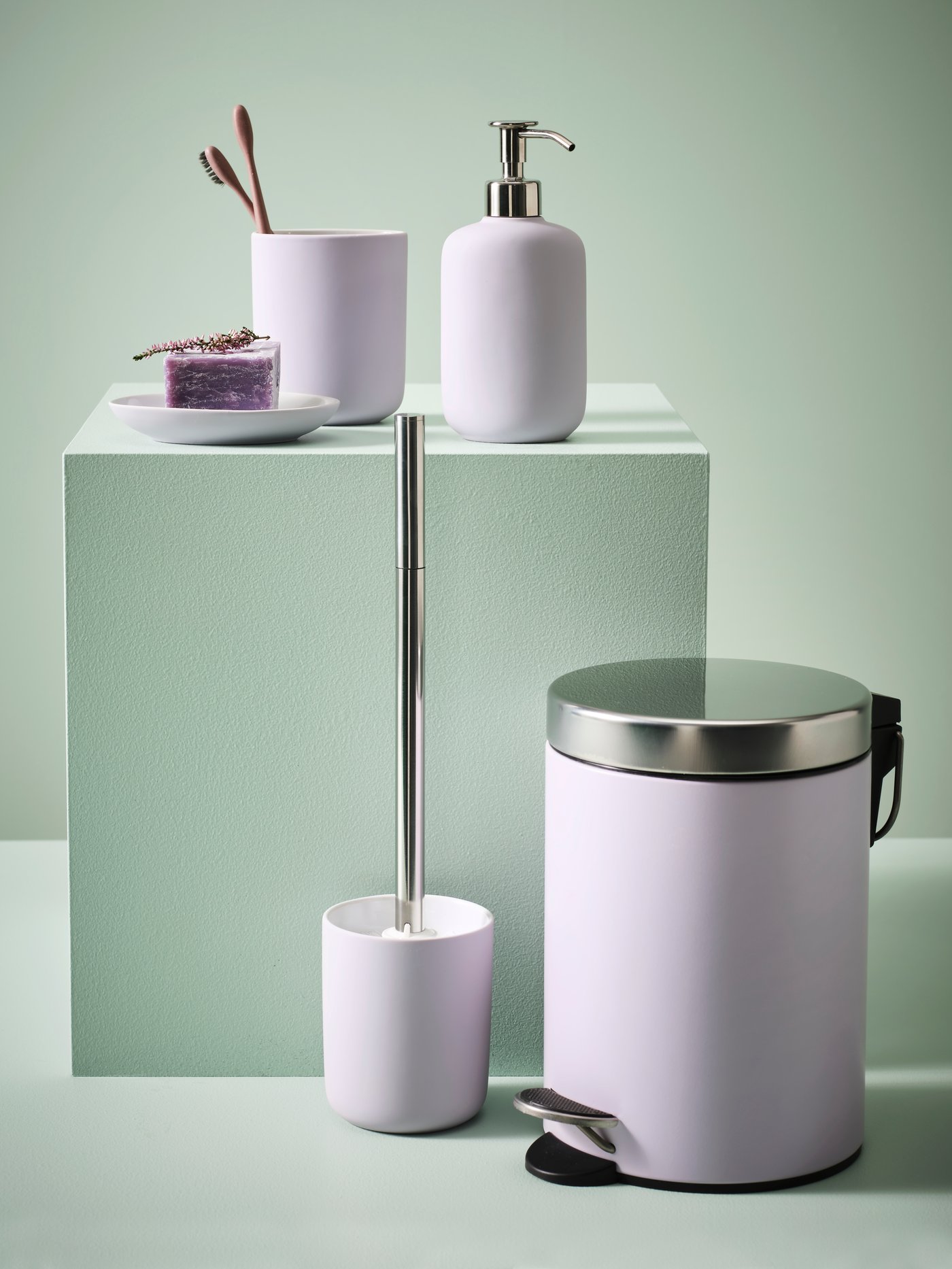 Distributeur de savon, porte-brosses à dents, brosse WC et poubelle à pédale EKOLN lilas, avec porte-savon et savon sur fond vert clair.