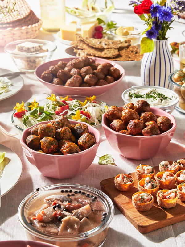 Midsommarmat står uppdukat på ett bord med köttbullar i fokus.
