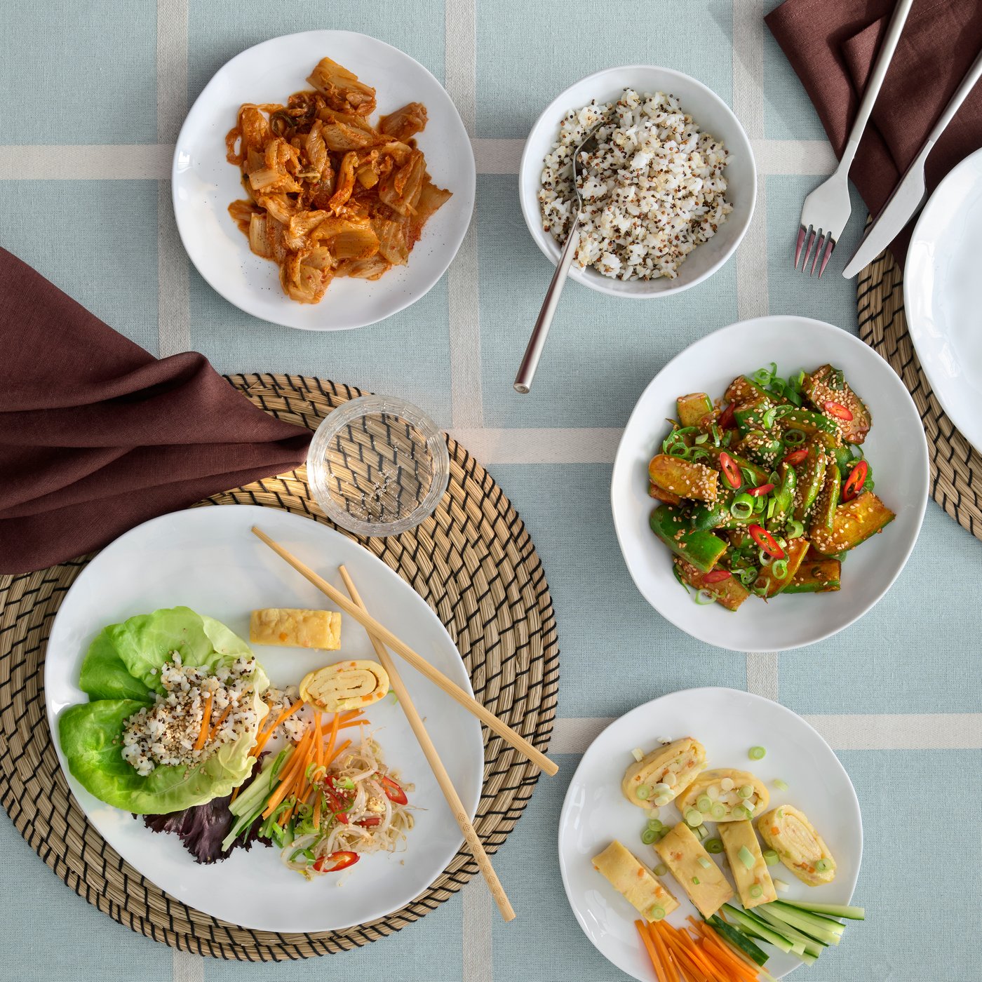A bird’s-eye view of a dining table shows dinnerware pieces from the FORELLTETRA series, filled with different kinds of food.