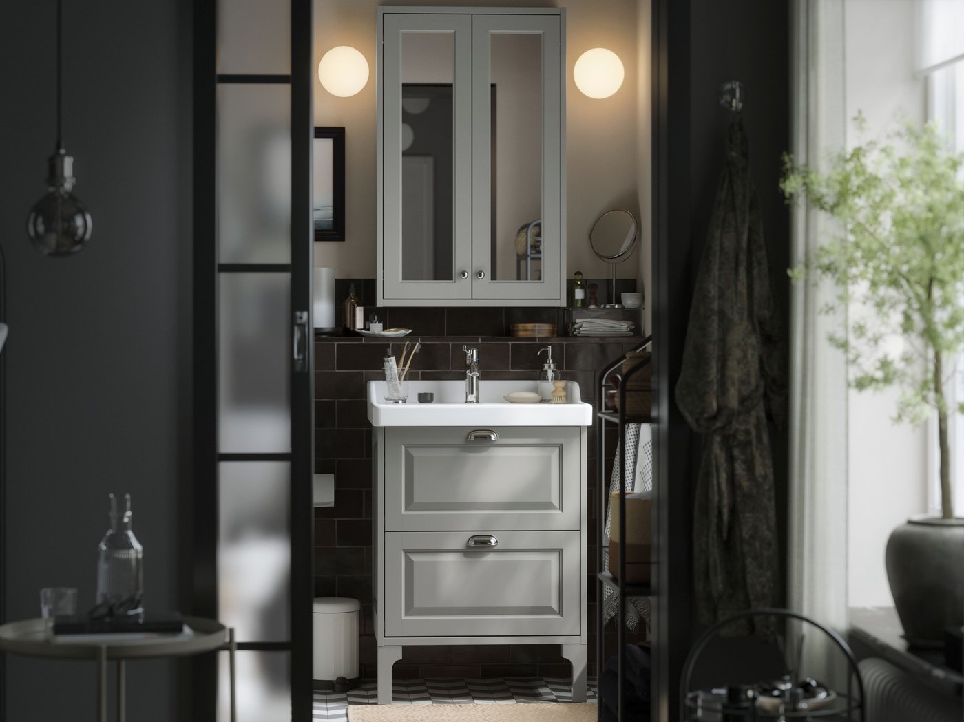 A small traditional style bathroom with white TÄNNFORSEN storage furniture, two soft round lamps and black details.
