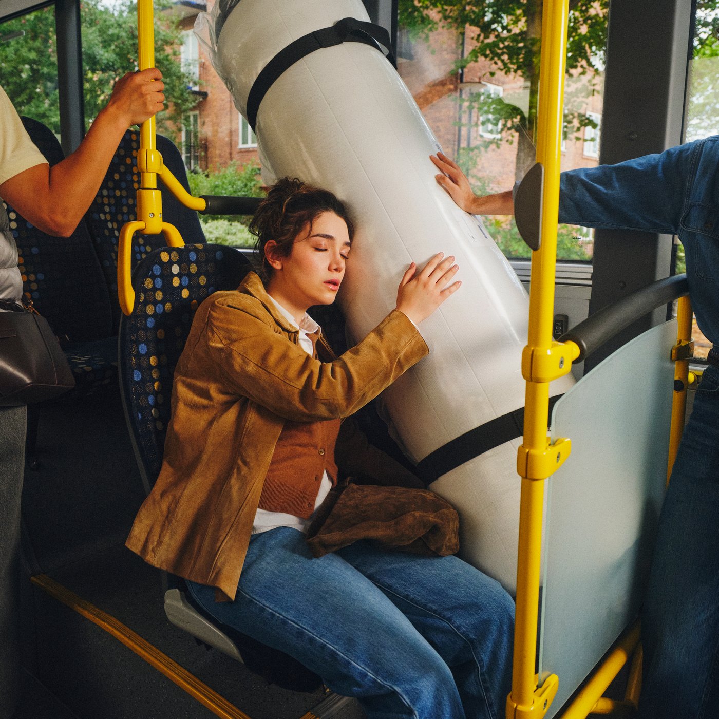 VALEVÅG pocket sprung mattress in its original roll pack is on a bus seat by a window. A person naps against the mattress.