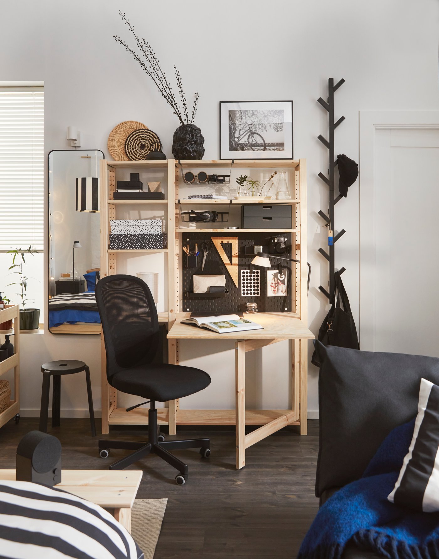 En kompakt arbetsplats med skrivbord och hyllförvaring som utnyttjar väggen för smart organisering i ett litet studentrum.