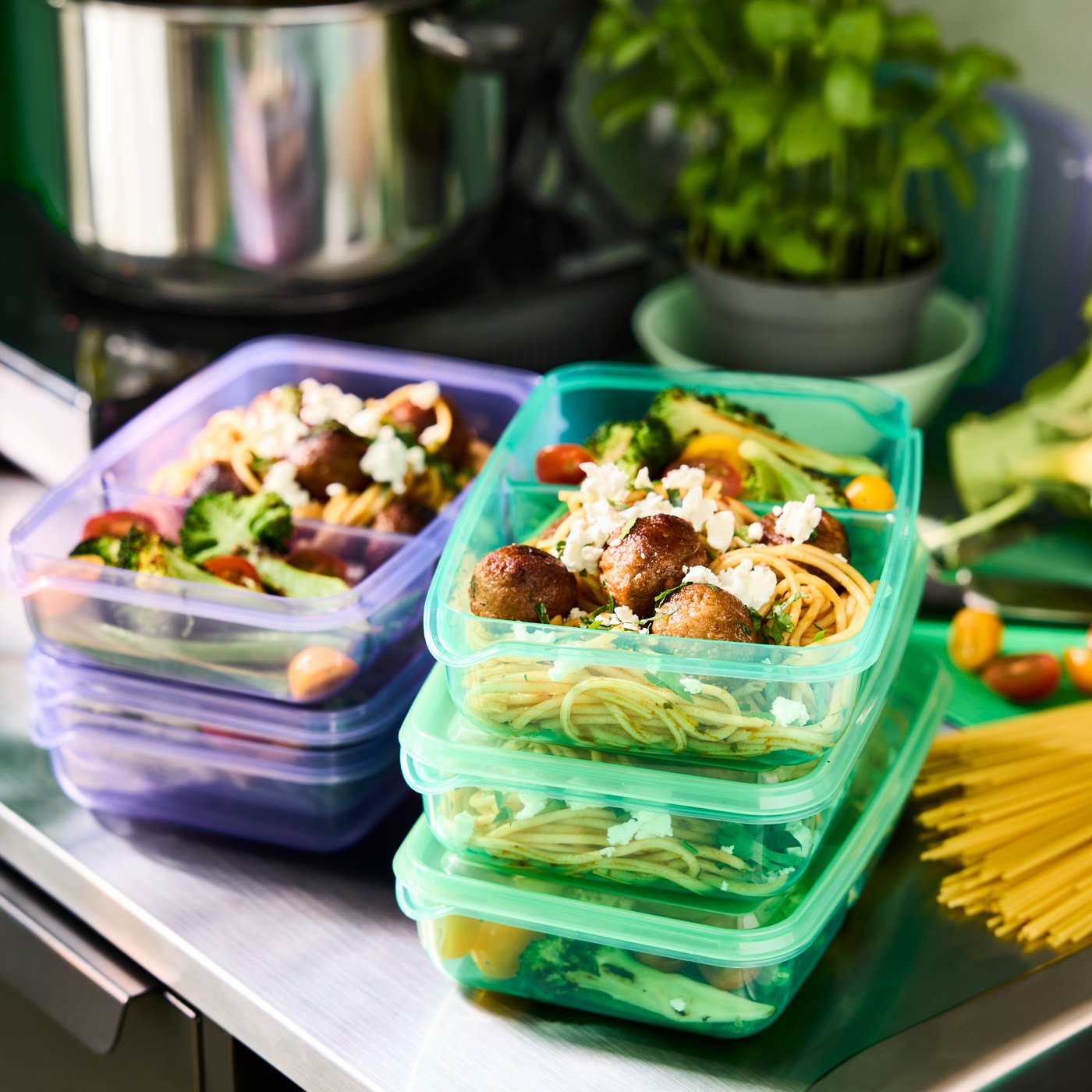 Lilac and green PRUTA sandwich boxes with two compartments prepped with pasta and vegetables.