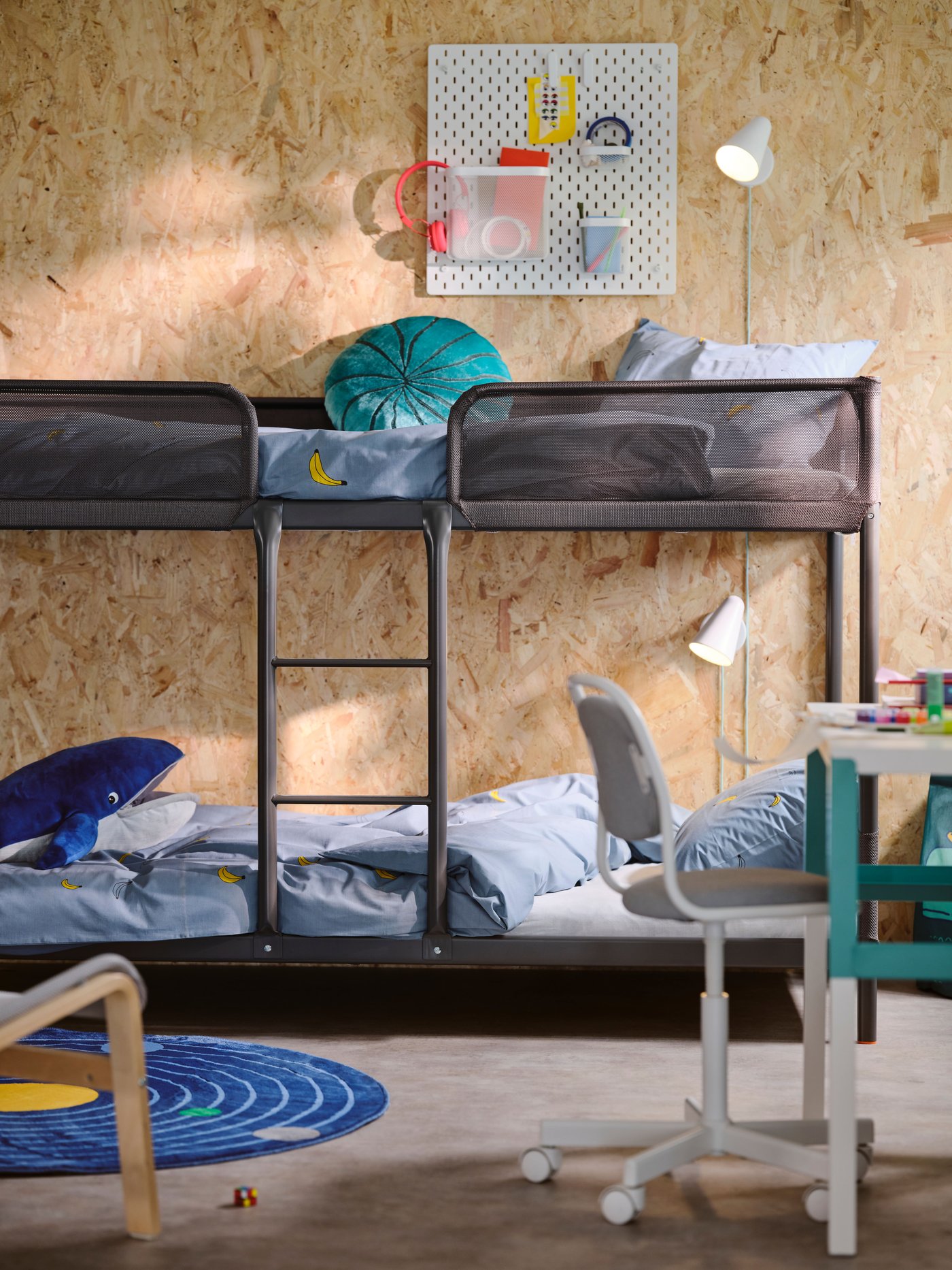 A dark grey TUFFNING bunk bed with pale blue VÄNKRETS bed linen on both beds and an AFTONSPARV rug on the floor in front.