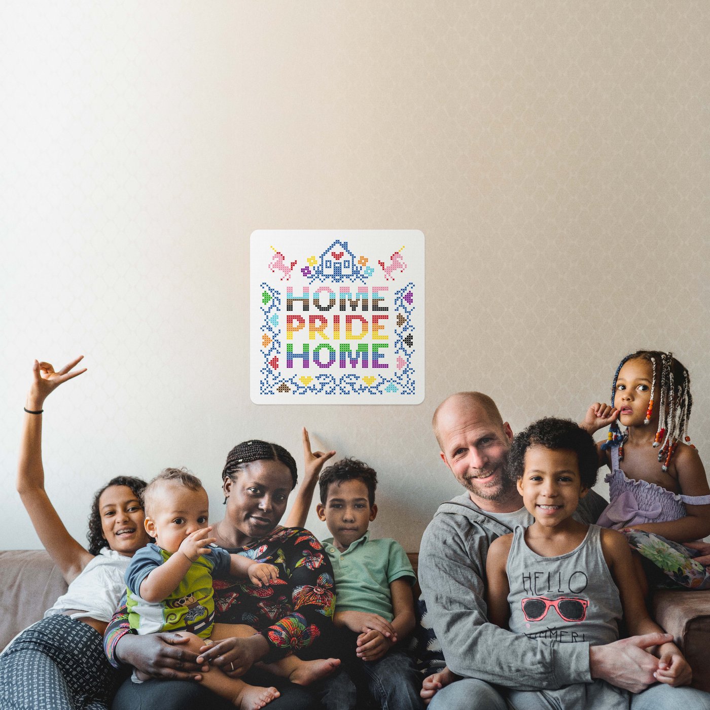 Porodica koju čine dva roditelja i petoro dece sedi na sofi sa znakom „Home Pride Home” na zidu iza njih.