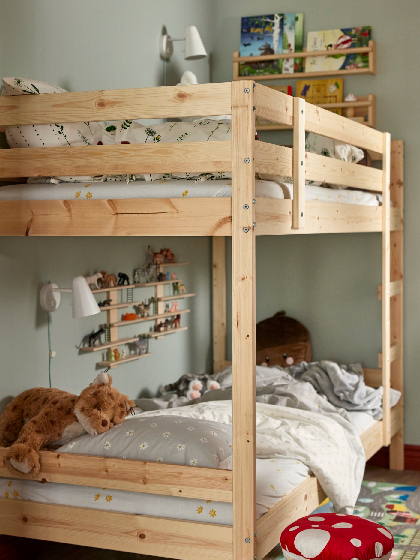 Child climbing up to the top of MYDAL bunk bed. The two beds have different decorations, shelfs and bedding.