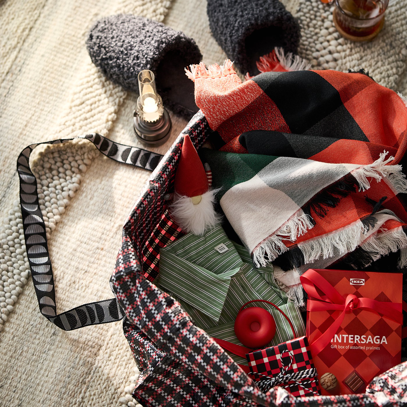 A VINTERFINT carrier bag filled with a VINTERFINT throw, a box of VINTERSAGA pralines and items for a guest staying over
