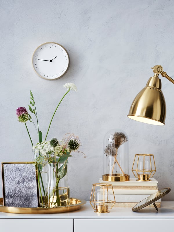Accessori per la casa in metallo e una composizione floreale su un mobile bianco - IKEA